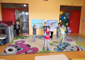 dzieci na dywanie wykonują polecenie nauczyciela w zabawie ruchowej