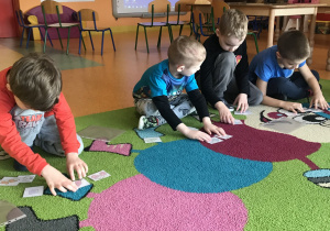 dzieci na dywanie układają obrazki w odpowiedniej kolejności