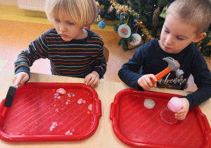 dzieci przy stolikach rozbijają kostki lodu i wyciągają zamarznięte skarby