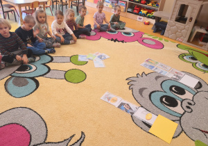 dzieci na dywanie układają ilustracje w odpowiedniej kolejności