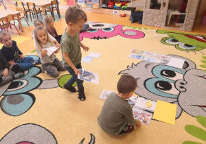 dzieci na dywanie układają ilustracje w odpowiedniej kolejności