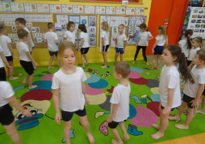 dzieci w strojach sportowych wykonują obroty na dywanie