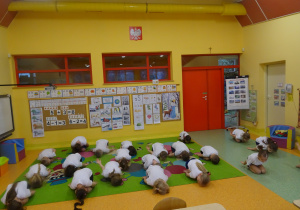 dzieci na dywanie wykonują ćwiczenia wskazane przez nauczyciela
