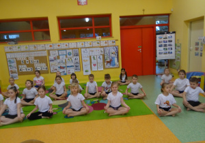 dzieci na dywanie wykonują ćwiczenia wskazane przez nauczyciela