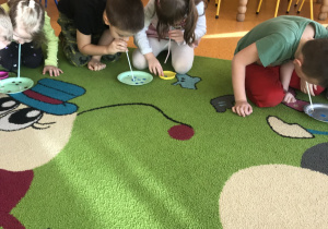 dzieci za pomocą słomek przenoszą kółeczka z talerzyka do pudełka