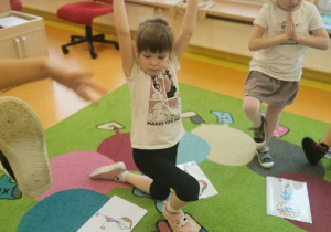 dzieci wykonują ćwiczenia zgodnie z ilustracją przy, której się zatrzymują