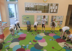 dzieci wykonują skłony na dywanie