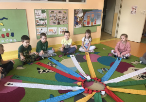 dzieci na dywanie zaczynają zabawy z wiatrakiem matematycznym, każdy przy swojej tasiemce