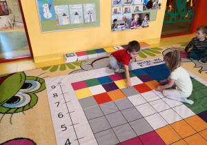 dzieci odwzorowują podany układu kolorowych tabliczek na macie współpracując w parach