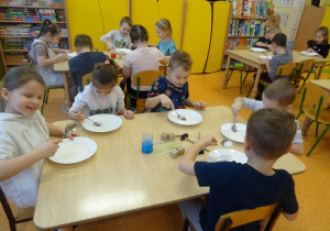 dzieci przy stolikach badały ciecz newtonowską i przenoszą ją łyżkami