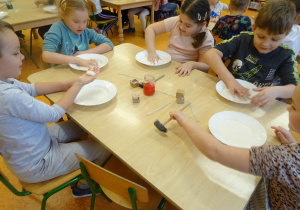dzieci przy stolikach badały ciecz newtonowską i starają się ją przenieść w dłoniach