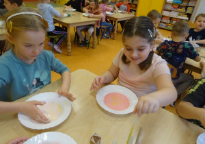 dzieci przy stolikach badały ciecz newtonowską i barwią ją farbą