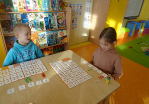 dzieci siedzą przy stolikach wykonują działania matematyczne na patyczkach