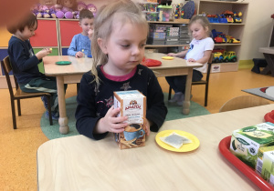dzieci siedzą przy stolikach starają się dopasować torebkę kawy lub herbaty z odpowiednim pudełkiem