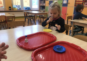 dzieci siedzą przy stolikach starają się dopasować zapach olejku z talerzyka z odpowiednią butelką
