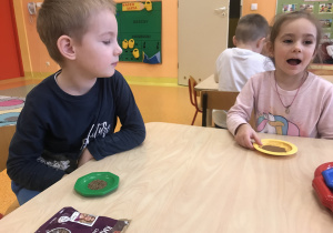 dzieci siedzą przy stolikach starają się dopasować przyprawę z odpowiednim opakowaniem