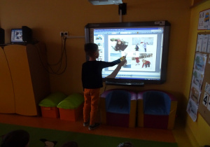 Chłopiec pisakiem zaznacza na ekranie interaktywnym odpowiedz czy dane sytuacje na obrazkach są bezpieczne