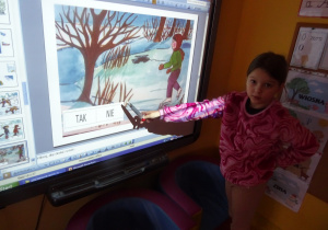 Dziewczynka pisakiem zaznacza na ekranie interaktywnym odpowiedz czy dane sytuacje na obrazkach są bezpieczne