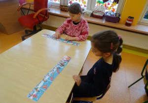 dzieci przy stolikach układają historyjki obrazkowe
