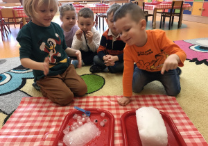 dzieci dotykają kostki lodu i bryłę śniegu