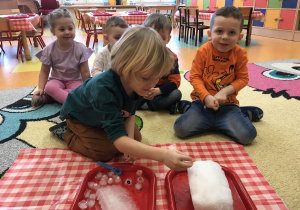 dzieci dotykają kostki lodu i bryłę śniegu