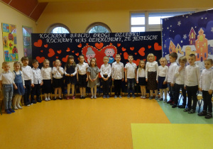 grupa dzieci stoi jedno koło drugiego i śpiewają razem piosenkę