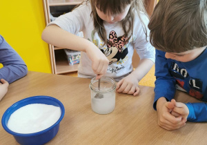 dzieci przygotowują roztwór potrzebny do doświadczenia, mieszają sól z wodą