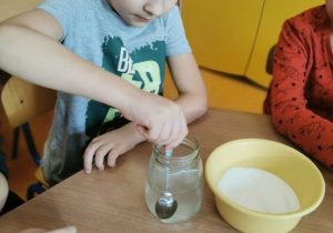 dzieci przygotowują roztwór potrzebny do doświadczenia, mieszają sól z wodą