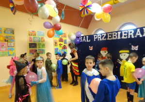 dzieci w strojach karnawałowych tańczą w parach trzymając między sobą napompowany balon