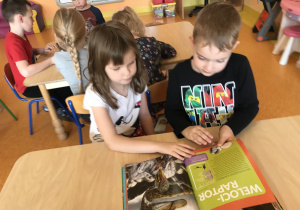 dzieci przy stoliku oglądają książki przyniesione przez Stasia