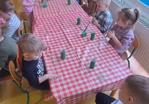 dzieci przy stolikach malowały zieloną farbą rolki po papierze toaletowym