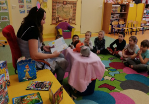 jedna z mam czyta dzieciom bajkę, pokazuje pluszowych bohaterów zająca, bobra i lisa, dzieci z uwagą słuchają