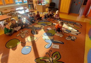 dzieci na dywanie przeliczały elementy na ilustracjach