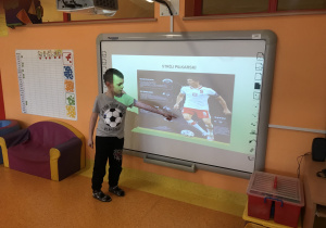 Szymon prezentuje dzieciom prezentacje multimedialną o piłkarzach