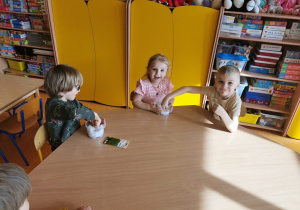 dzieci przy stolikach sieją rzeżuchę na wacie w plastikowych pojemnikach