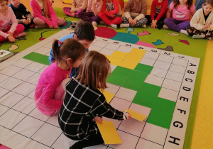 grupa układa kolorowe tabliczki według kodu na macie do kodowania