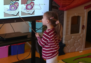 dziewczynka na ekranie wskazuje różnice na obrazku, którym są pisanki