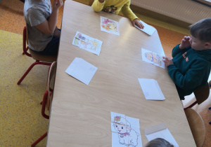 dzieci przy stolikach układają puzzle związane z tematyką Wielkanocy