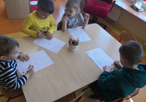 dzieci przy stolikach wykonują kartę pracy, połącz kropki