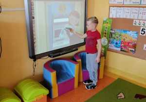 chłopiec na tablicy wskazuje opisywany przez nauczyciela obrazem