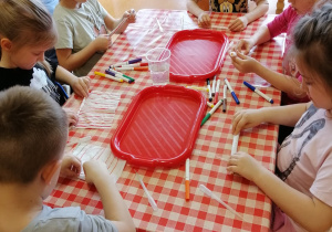 dzieci zwijają pomalowaną chusteczkę higieniczną w rulon