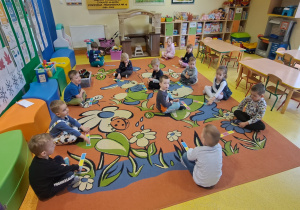 dzieci na dywanie przyglądają się kartą przygotowanym przez nauczyciela dotyczących rytmów