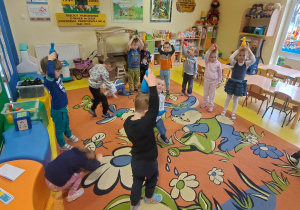 dzieci na dywanie ćwiczą równowagę za pomocą kolorowych kręgli