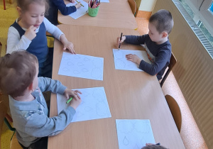 dzieci przy stolikach łączą kroki na kartach pracy by powstała ilustracja