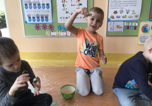 dzieci mieszają składniki w miseczkach tworząc ciecz nienewtonowską oraz mokry piasek