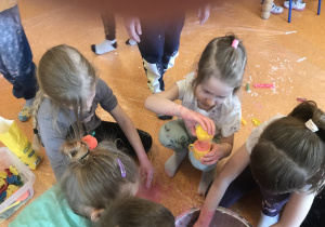 dzieci mieszają składniki w miseczkach tworząc ciecz nienewtonowską oraz mokry piasek