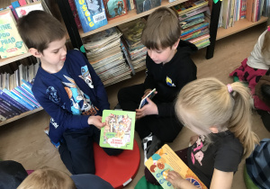 dzieci oglądają książki zgromadzone w bibliotece