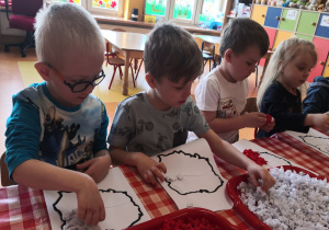 dzieci przy stolikach wypełniają kontur Polski kulkami z bibuły