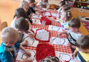 dzieci przy stolikach wypełniają kontur Polski kulkami z bibuły