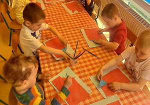 dzieci przy stolikach na niebieską kartkę przyklejają trójką niebieski wg polecenie nauczyciela
